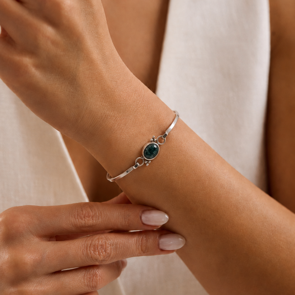Silver bracelet with a jade stone on a wrist against a neutral background