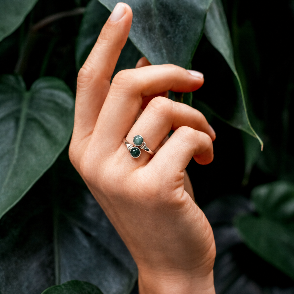 Hand wearing a jade ring against a leafy background