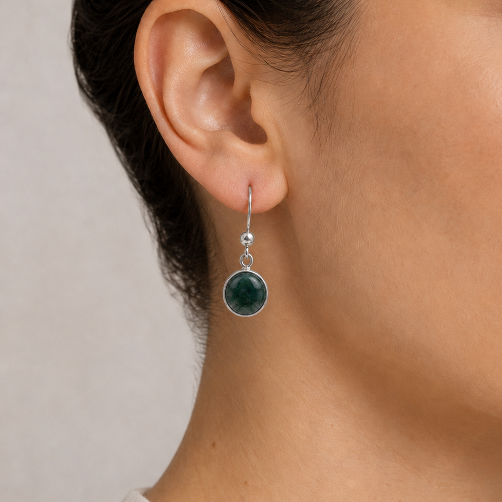 Close-up of a woman wearing jade circle earrings with a neutral background