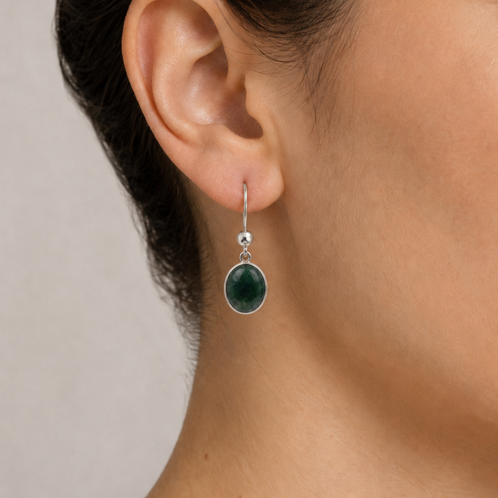 Close-up of a woman wearing jade earrings with a neutral background
