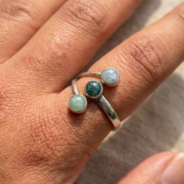 Silver ring with three jade stones on a person's finger