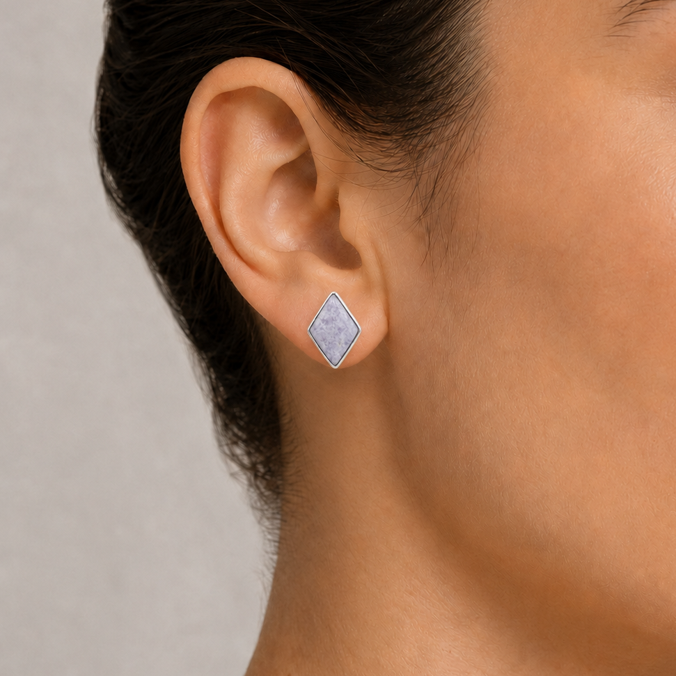 Close-up of a woman wearing a silver earring with a jade gemstone on a neutral background