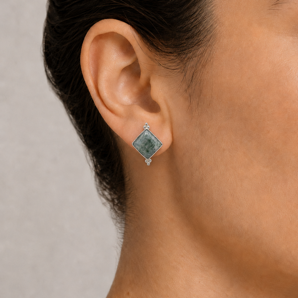 Close-up of a woman wearing a moss jade earring with a neutral background